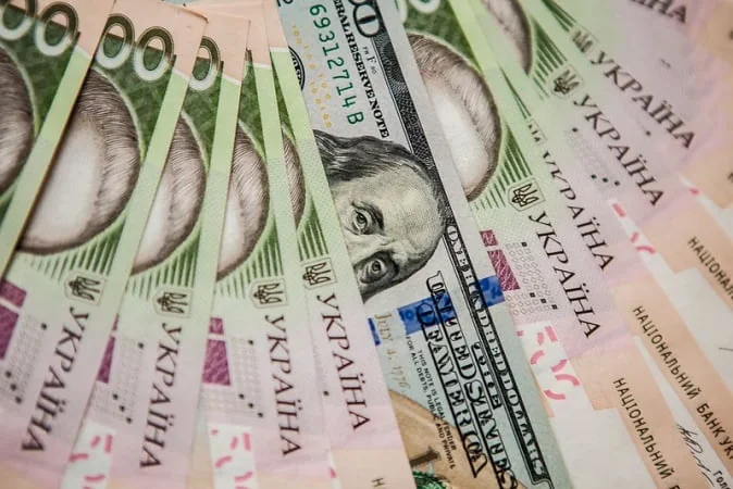 Банкноти доларів США та гривні на тлі курсу НБУ 16 липня
