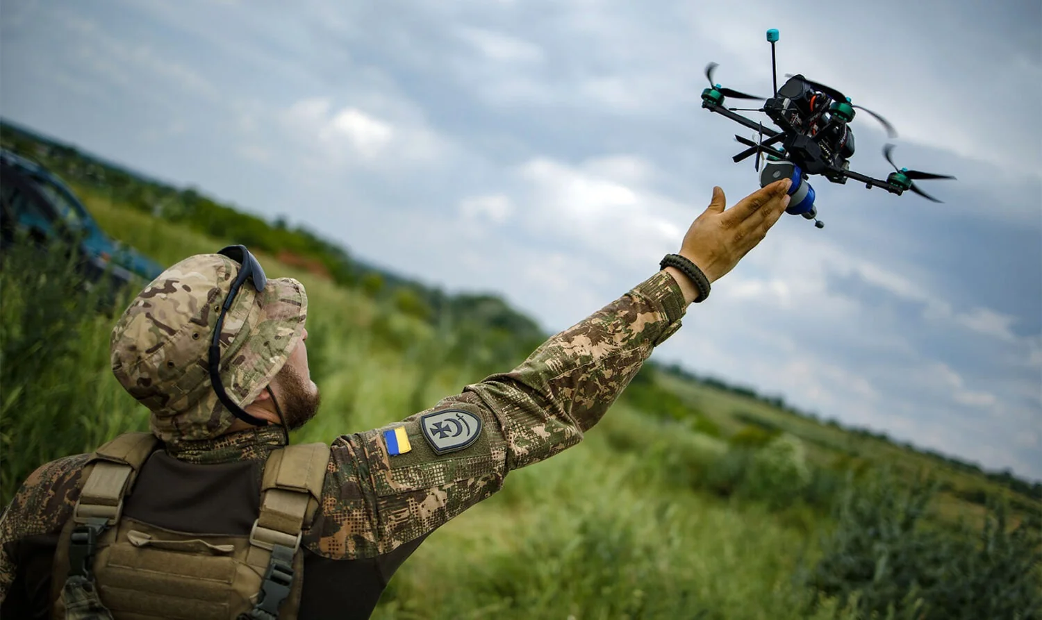 Український військовий тримає дрон на фоні поля, демонструючи технології для співпраці зі США