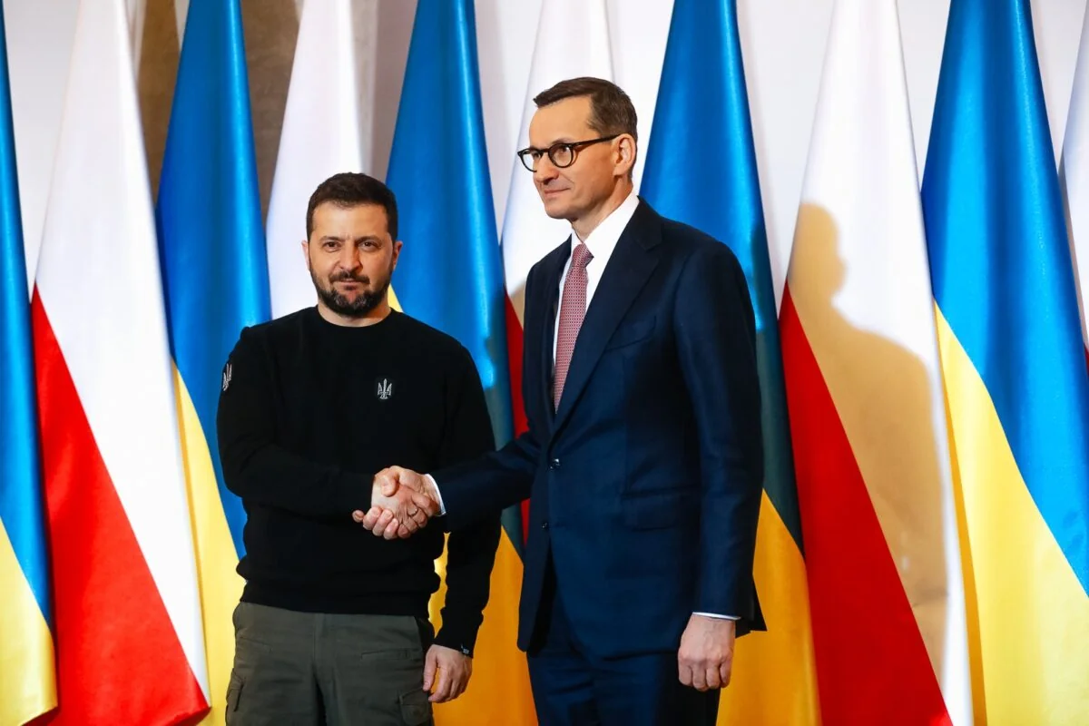 Президент України та премєр Польщі тиснуть руки на тлі прапорів двох країн