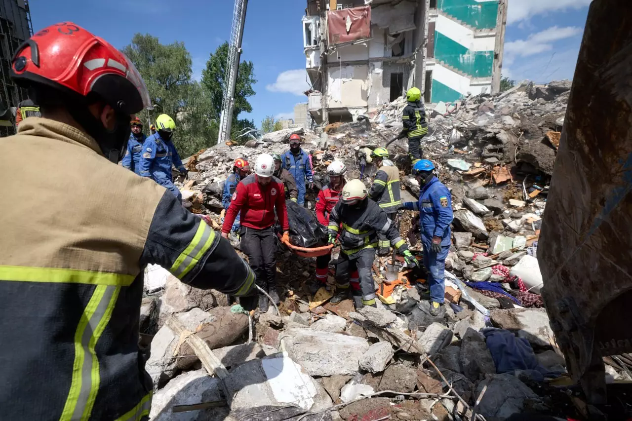 Рятувальники несуть загиблого з руїн житлового будинку в Києві після удару