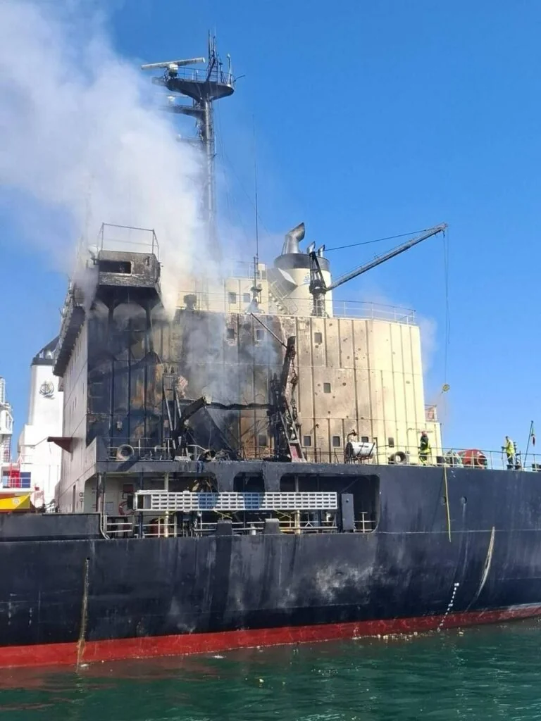 Пошкоджене судно після удару в порту Одещини з димом від пожежі