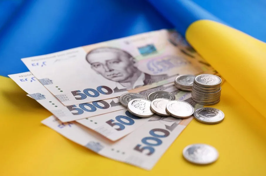 Українські банкноти 500 гривень та монети на синьо-жовтому тлі