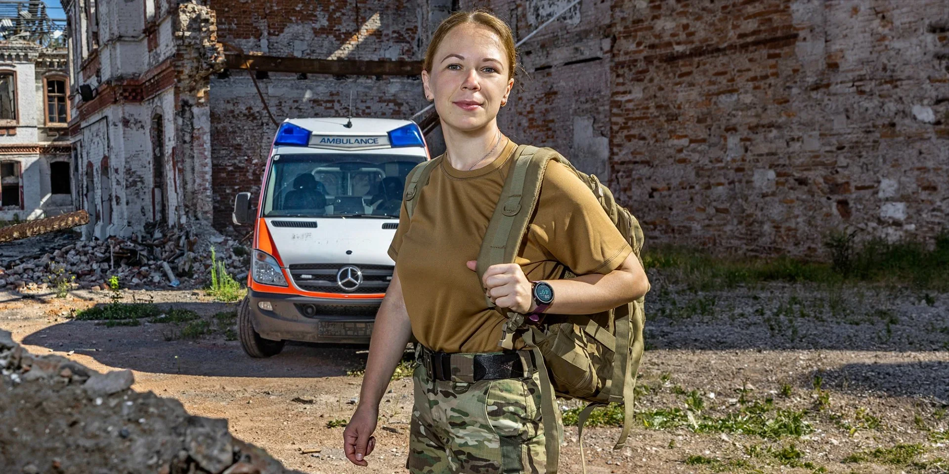 Медикиня «Літа» біля пошкодженого медеваку на тлі зруйнованої будівлі