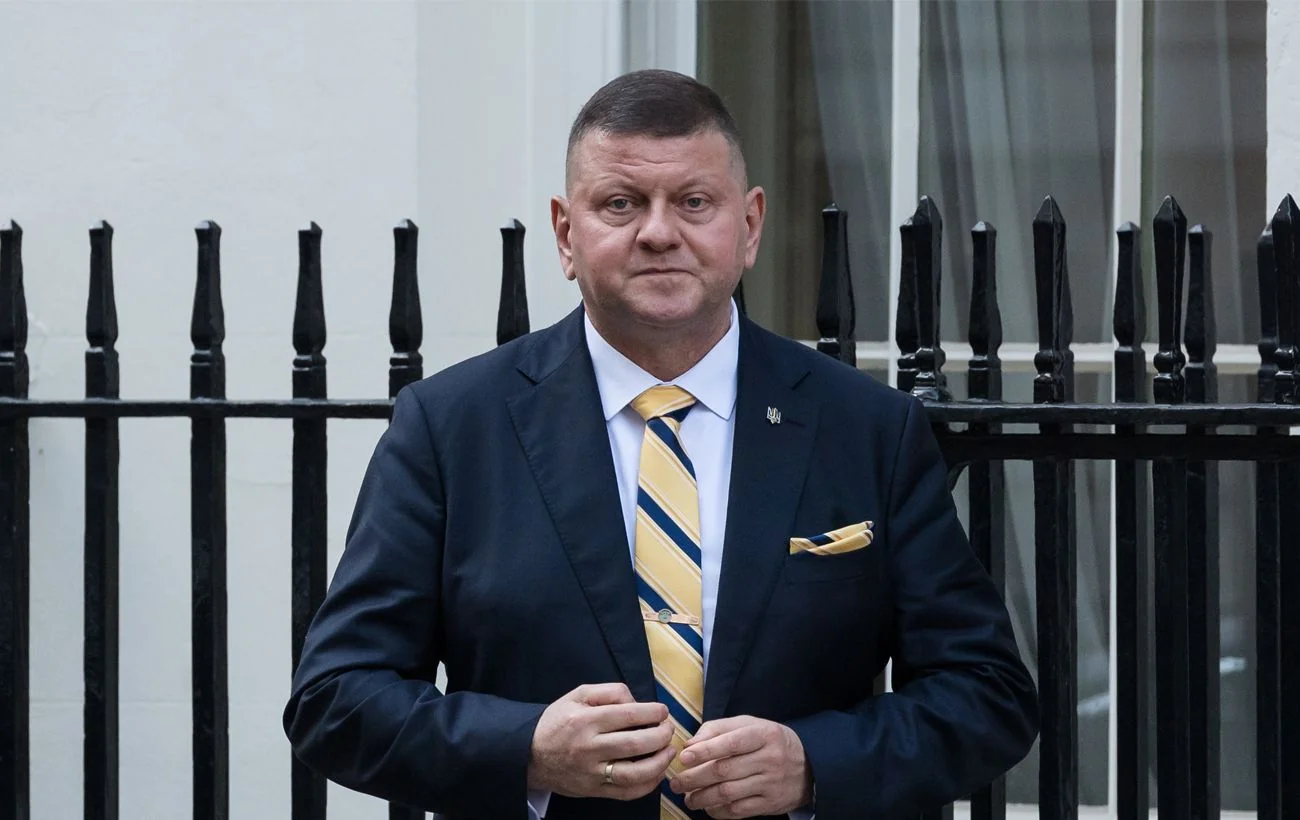 Валерій Залужний у синьому костюмі з жовто-синьою краваткою біля чорної огорожі